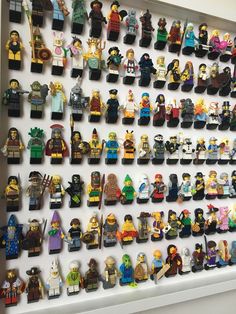 a wall full of lego minifigures on display in a room with white walls