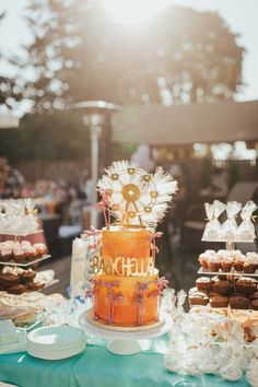 an orange cake sitting on top of a table covered in pastries and desserts