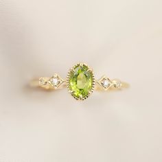 * ≈6x4mm oval peridot * Band width: ≈1.3mm * G color SI diamonds, ≈0.04ctw * Setting style: Prong setting, low profile (sits flush on your finger) * Material: Solid 14k yellow gold, rose gold or white gold * Made of 100% recycled precious metal and ethically sourced gemstone * Comes in a gift box with a bow ready for gifting * Handmade with love and great care in New York * Please note that colors may vary slightly as they are genuine gemstones. Our Dedication All our jewelry is designed and cre Green Peridot Birthstone Ring, Dainty Style, Lime Green Peridot Ring For May Birthstone, Lime Green Peridot Birthstone Ring For May, Dainty Green Peridot Rings, Peridot Birthstone Diamond Ring Fine Jewelry, Lime Green Peridot Birthstone Ring, Fine Jewelry Peridot Birthstone Ring With Center Stone, Peridot Diamond Ring For May Birthstone, Yellow Gold Peridot Birthstone Ring