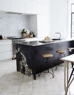 a kitchen with marble counter tops and stools next to an island in the middle