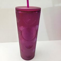 a purple cup with a straw in it on a white table next to a wall