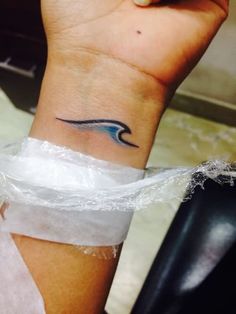 a woman's wrist with a wave tattoo on the left side of her arm