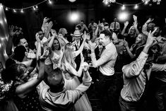 a group of people standing around each other on top of a dance floor with their hands in the air