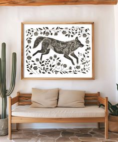 an animal print hangs on the wall next to a couch with pillows and cacti