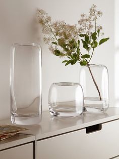 two clear vases sitting on top of a white dresser