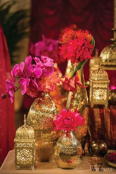 several vases with flowers in them sitting on a table next to other decorative items