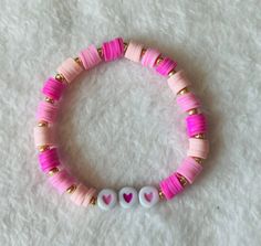 Heishi/clay beaded bracelet: Pink hearts  -good quality -very stretchy -one size: about 6.5 inches (can stretch to around 8 inches)  This bracelet contains various shades of pink heishi/clay beads, gold sead beads, and two shades of pink heart beads upon very stretchy string.  This bracelet comes in one size (measures about 6.5 inches) and is meant to fit people with small and medium size wrists. If you have a larger wrist than about 8 inches, then send me a message to get a custom bracelet. Cute Heishi Beads Friendship Bracelets, Playful Pink Heishi Beaded Bracelets, Trendy Pink Heishi Beads Friendship Bracelet, Trendy Heart-shaped Stretch Bracelet With Letter Beads, Pink Stretch Bracelet With Letter Beads For Valentine's Day, Pink Heishi Beaded Bracelets With Letter Beads, Pink Heishi Beads Bracelet With Letter Beads, Playful Pink Heishi Beads Bracelets, Playful Pink Heishi Beads Stretch Bracelet