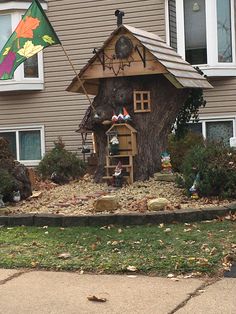 a house made out of a tree stump with a flag flying in the wind next to it