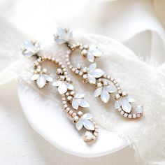 Complete your bridal look with our beautiful floral bridal earrings.  Created in a romantic style that is perfect for a boho bride or for a pop of glam to a classic bride.   - Handcrafted with genuine Austrian crystal - Each stone is set by hand in my studio - White opal crystals - Antique gold finish pictured - Available in rose gold, antique gold and rhodium (silver) finishes - Earrings measure 3 inches x 7/8 inch - Handcrafted in the US. - Nickel free and hypoallergenic - PLEASE ALLOW APPROX Elegant White Earrings For Wedding Reception, Elegant White Bridal Earrings For Wedding Reception, Elegant Flower Crystal Earrings For Wedding, Glamorous Flower Earrings For Wedding, Delicate Drop Earrings For Bridal Shower, Glamorous White Crystal Wedding Earrings, Delicate Dangle Cluster Earrings For Wedding, White Crystal Earrings For Wedding, White Dangle Earrings For Brides