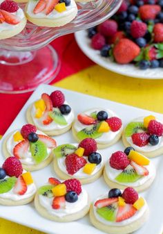 small desserts are arranged on a white platter with fruit and kiwi slices