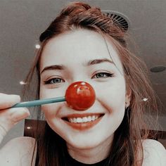 a girl with a nose ball on her nose holding a toothbrush in front of her face