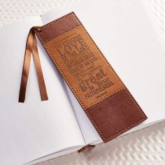 an open book with a brown leather cover and writing on the front is sitting on a white surface