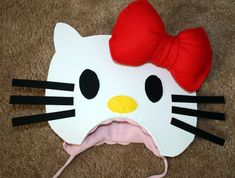 a hello kitty mask with a red bow on it's head is laying on the floor