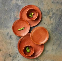 three brown bowls with green peppers in them on top of a gray tableclothed surface