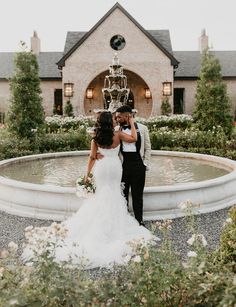 a bride and groom standing in front of a fountain