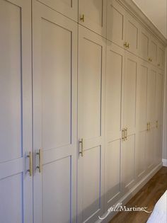 an empty room with white cabinets and wood floors