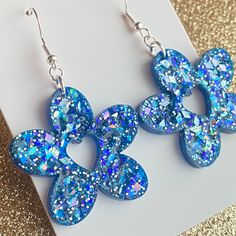 These stunning Blue Glitter Heart and Flower Handmade Resin Earrings are the perfect addition to any jewelry collection. These earrings are crafted with care and feature a beautiful blue glitter design with hypoallergenic hooks that make them comfortable to wear for extended periods. These earrings showcase a unique flower and heart shape that adds an extra touch of elegance to your outfit. The handmade resin construction ensures durability, making these earrings perfect for everyday wear. Ideal for the spring season, these Blue Glitter Heart and Flower Earrings are an excellent way to bring some color into your wardrobe. The subtle glitter design adds some sparkle, accentuating your style while still maintaining a sophisticated look. In summary, if you're looking for stylish Spring access Blue Heart-shaped Earrings For Party, Blue Flower Earrings With Ear Wire For Party, Blue Heart Drop Earrings For Party, Blue Dangle Heart Earrings For Party, Blue Heart-shaped Drop Earrings For Party, Blue Flower-shaped Resin Earrings, Sparkling Flower Earrings As Gift, Sparkling Blue Dangle Earrings, Blue Glitter Jewelry For Party