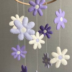 purple and white felt flowers hanging from a wooden hoop