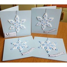 three snowflakes are hanging from cards on a table