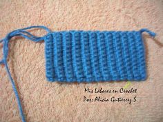 a blue crochet bag sitting on top of a towel next to a thread