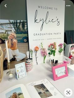 a table topped with pictures and flowers next to a sign that says, welcome to kylie's graduation party