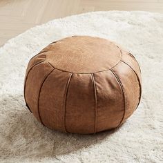 a brown leather poufce sitting on top of a white rug