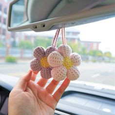 someone is holding up some crocheted flowers on the dashboard of a car,