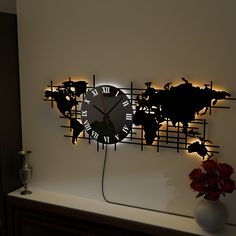 a clock that is on the side of a wall next to a vase with flowers