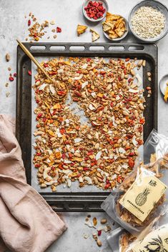 an overhead shot of granola on a baking sheet with ingredients to make the granola