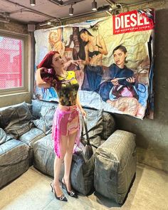 a woman standing in front of a couch next to a poster