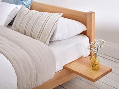 a wooden bed with white sheets and pillows