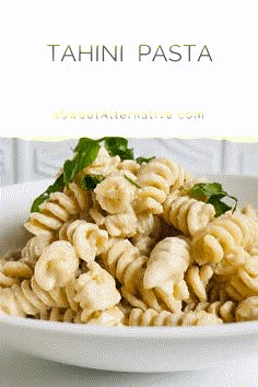 a white bowl filled with pasta and garnished with basil