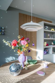 a wooden table topped with vases filled with flowers and disco ball lights hanging from the ceiling