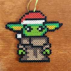 a christmas ornament made out of perler beads on a wooden table with a green ribbon