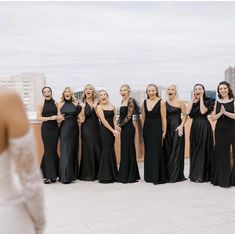 a group of women standing next to each other on top of a roof in dresses