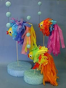 three colorful fish on sticks with pom poms