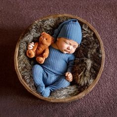 a baby is sleeping in a basket with a teddy bear