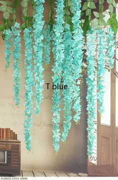 blue flowers are hanging from the ceiling in front of a tv and bookshelf