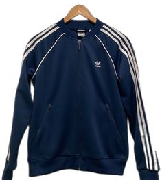 Navy Track Jacket For Spring Streetwear, Classic Long Sleeve Track Jacket For Spring, Casual Blue Adidas Outerwear, Casual Blue Track Jacket For Winter, Casual Blue Winter Track Jacket, Blue Track Jacket With Ribbed Cuffs For Winter, Blue Winter Track Jacket With Ribbed Cuffs, Winter Blue Track Jacket With Ribbed Cuffs, Blue Track Jacket With Ribbed Cuffs For Fall