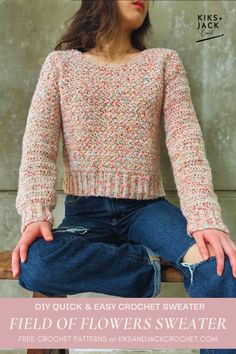 a woman sitting on top of a wooden bench wearing jeans and a knitted sweater