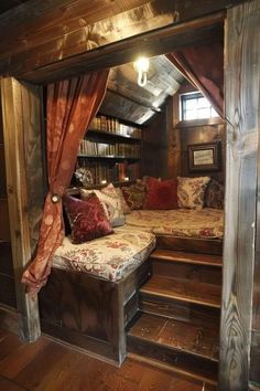 a bed sitting in the middle of a room under a wooden roof with red curtains