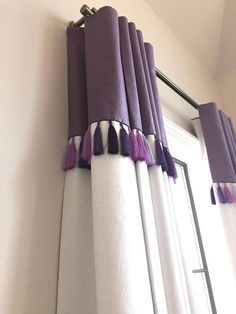 purple and white curtains hanging on the side of a window