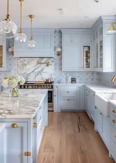 a kitchen with blue cabinets and marble counter tops, gold pulls on the cabinet doors