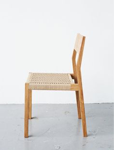 a wooden chair with woven seat and backrests in front of a white wall