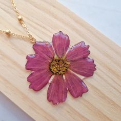 a pink flower is hanging from a gold chain