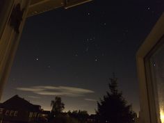 the night sky is lit up with stars and clouds in the distance as seen from an open window