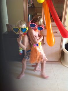 two young children standing next to each other wearing swim goggles and holding inflatable balloons