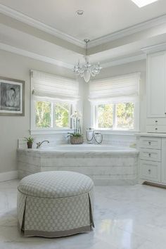 a large white bathroom with two windows and a chandelier