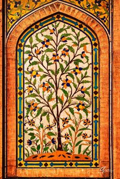 an intricately decorated wall with a tree in the middle and colorful tiles on it