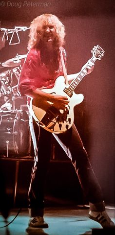 a man with long hair playing an electric guitar